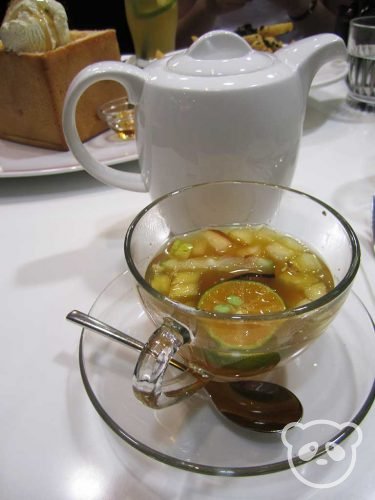 Fruit tea in a teacup with tea pot.