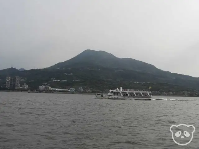 Tamsui ferry in front of mountain scenery.