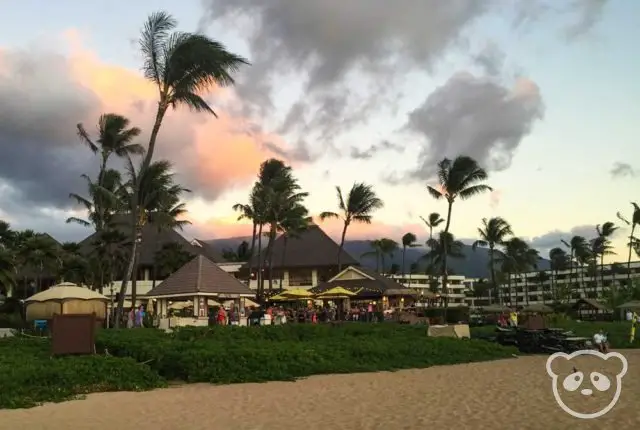 Restaurant and bar just off of the beach with clouds and palm trees in the background.